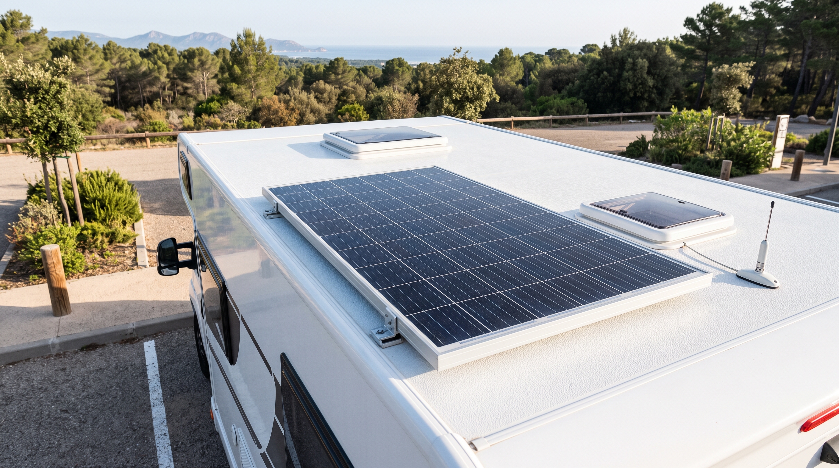 Autocaravana estacionada en un área habilitada, con una placa solar instalada en el techo y vegetación mediterránea al fondo.